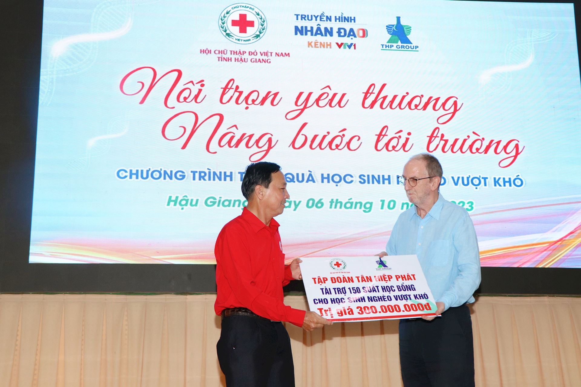 Ông David Riddle trao bảng tượng trưng 150 suất học bổng cho ông Nguyễn Chí Nghề - Chủ tịch Hội Chữ thập đỏ tỉnh Hậu Giang